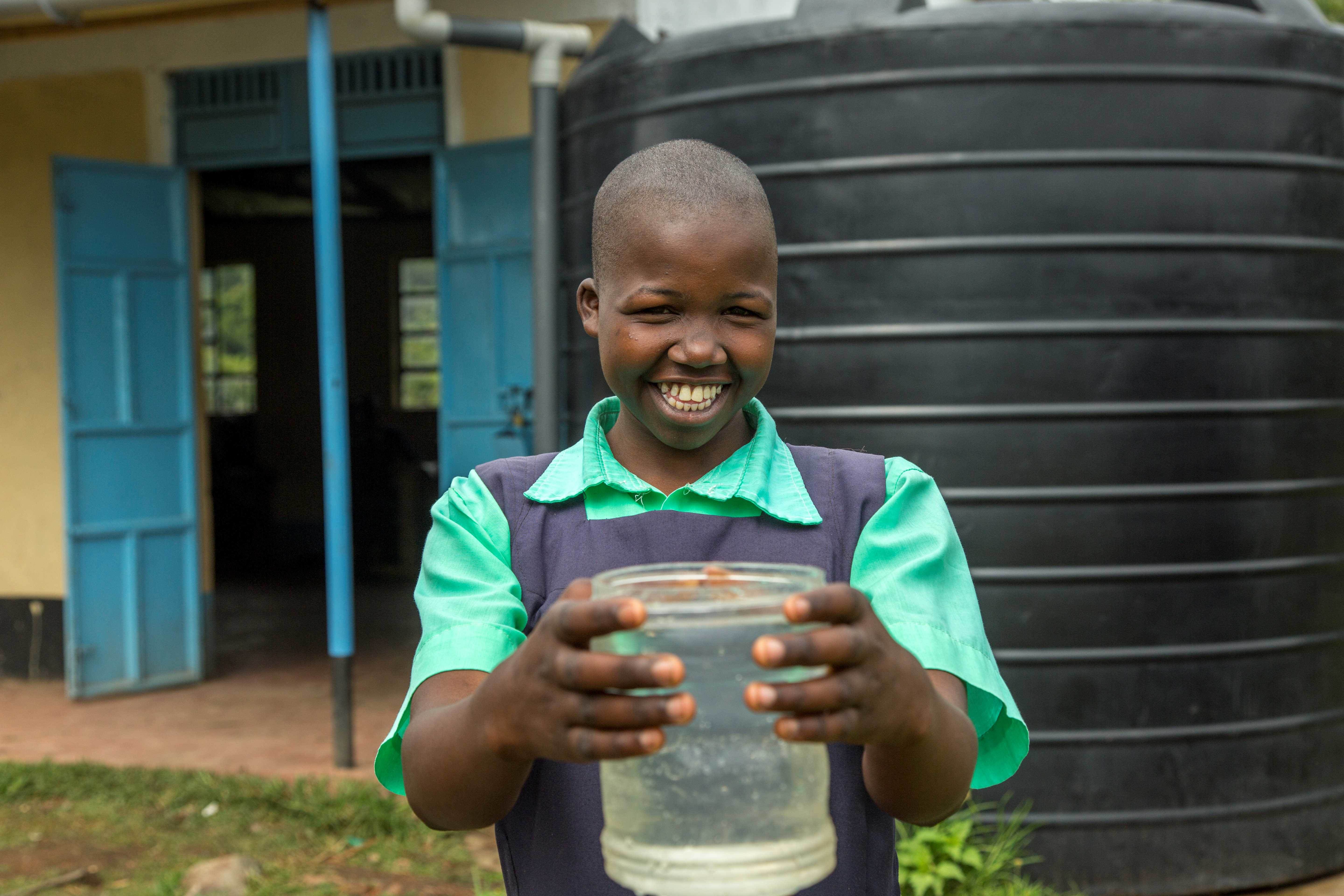 Student holding container of clean water thanks to Dig Deep